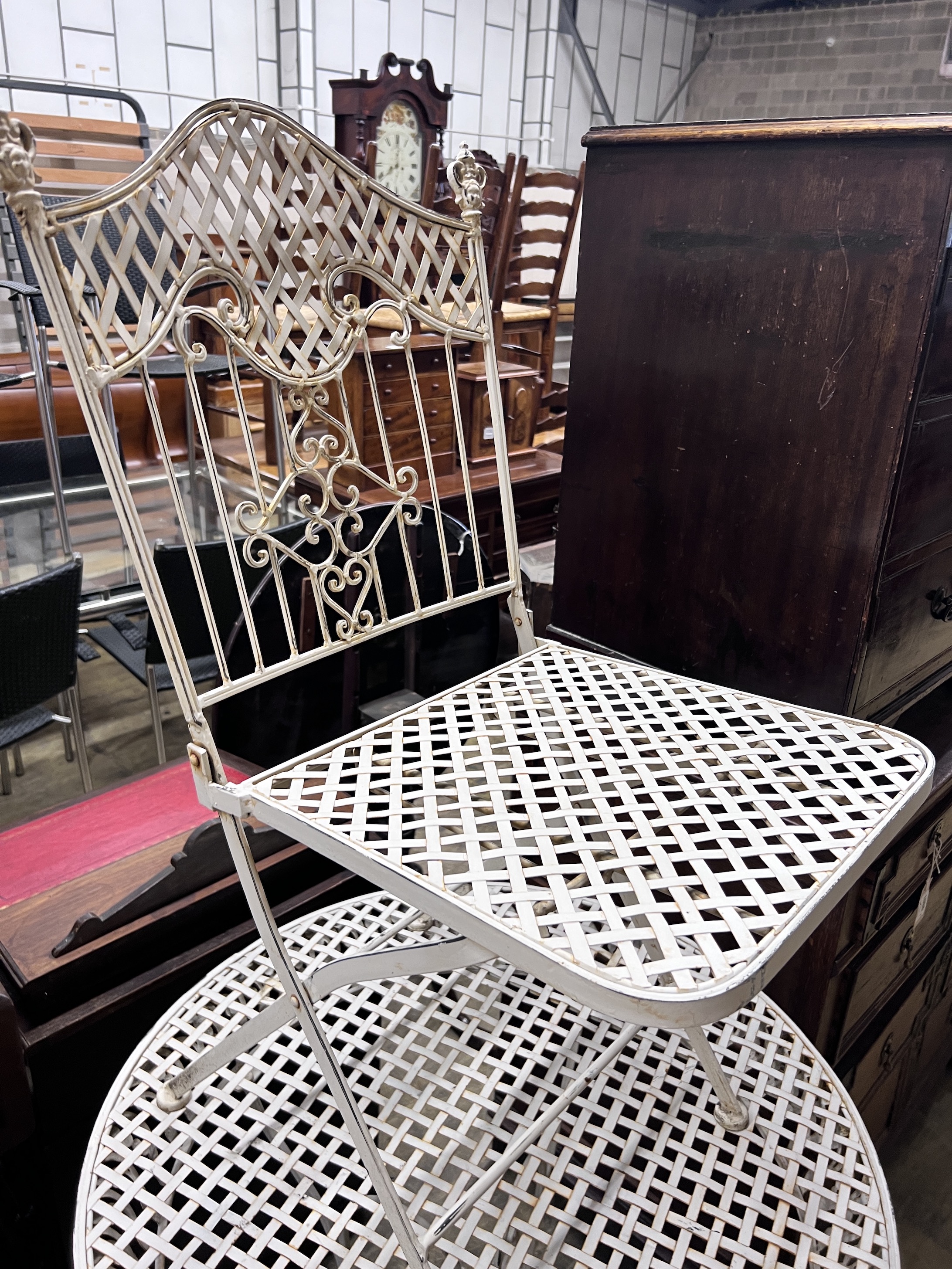 A white painted wrought iron garden table and four folding chairs